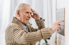[Translate to English-GB:] Old man touching his forehead standing infront of an button panel