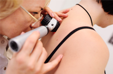 [Translate to English-GB:] Physician looking on skin of patient with an miscroscope instrument