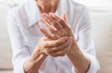 [Translate to English-GB:] Person in white blouse holding left hand with right hand